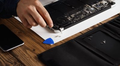 Electronic repair service Close focus on hand that uses angled esd tweezers to remove dust from electronic boards of broken slim computer laptop to fix it and make to work again.