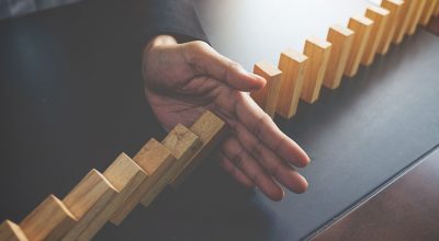 Problem Solving,Close up view on hand of business woman stopping Problem Solving,Close up view on hand of business woman stopping falling blocks on table for concept about taking responsibility.